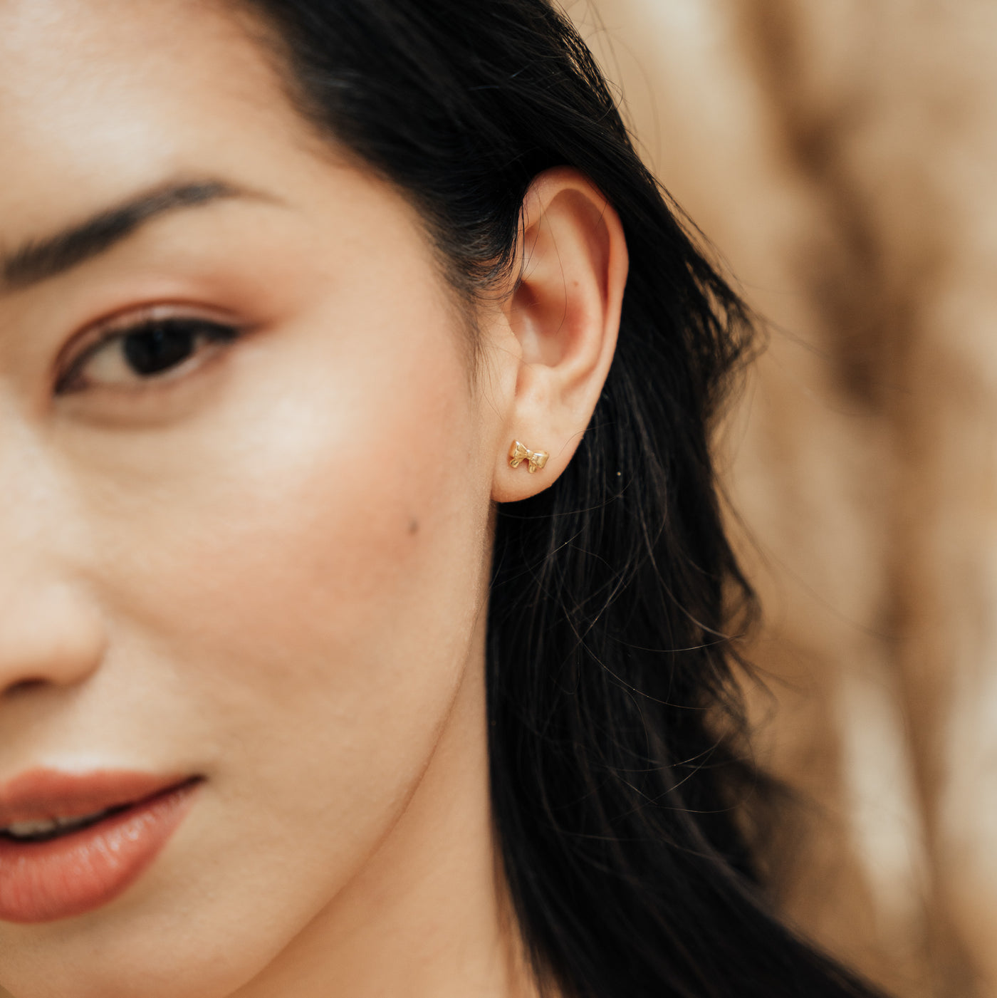 Close-up of a woman’s face wearing the Ribbon Bow Stud Earrings.