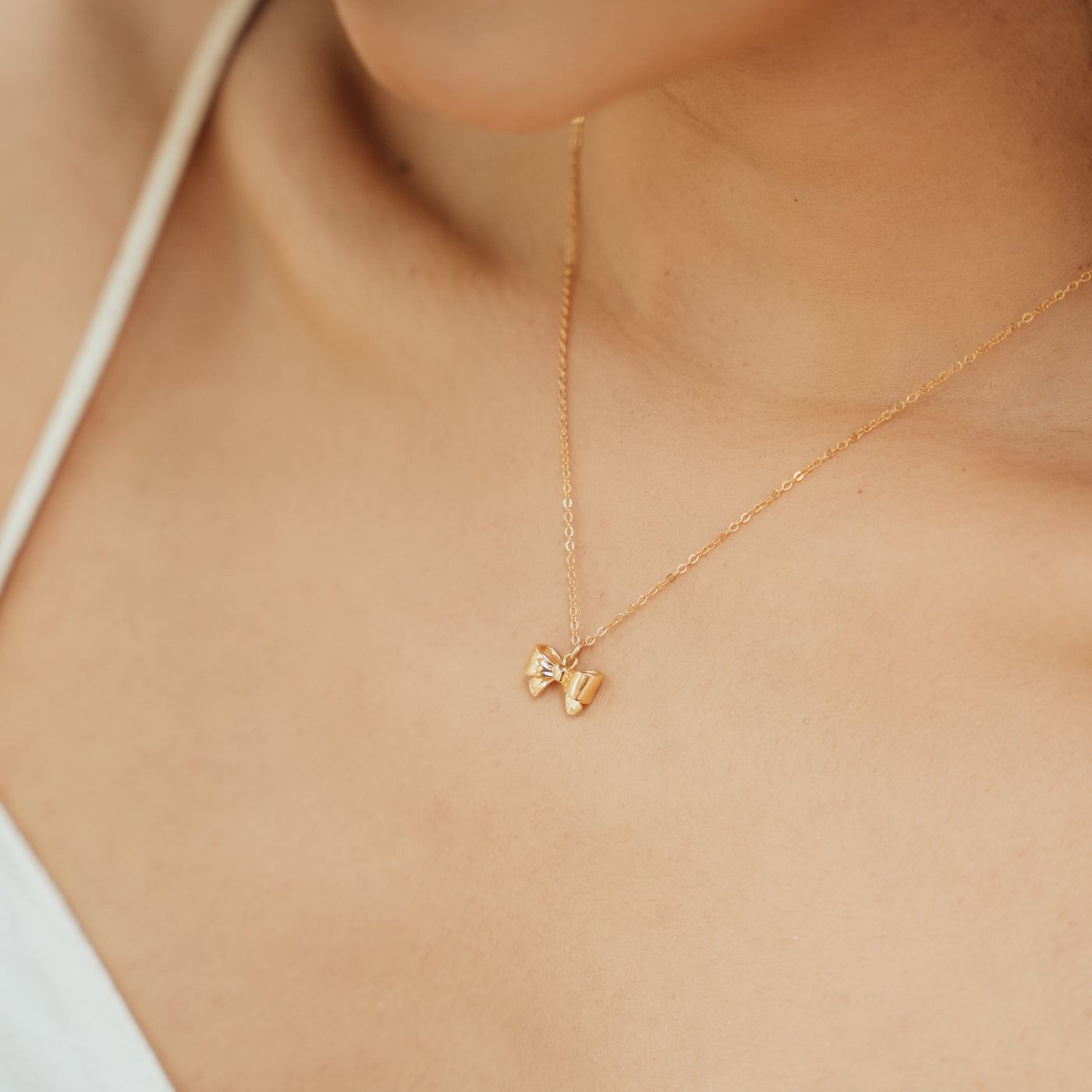 Close-up of a woman’s chest wearing the Ribbon Bow Necklace.