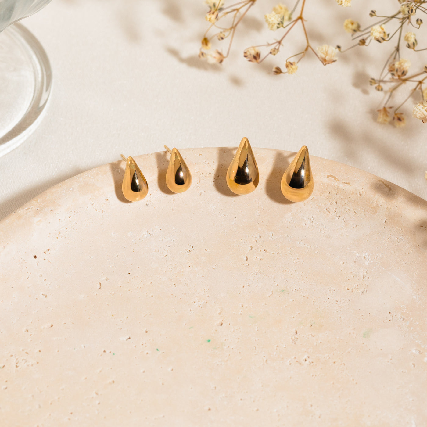 Small Large Teardrop Stud Earrings Small teardrop stud earrings and large teardrop stud earrings lying on the edge of a stone surface