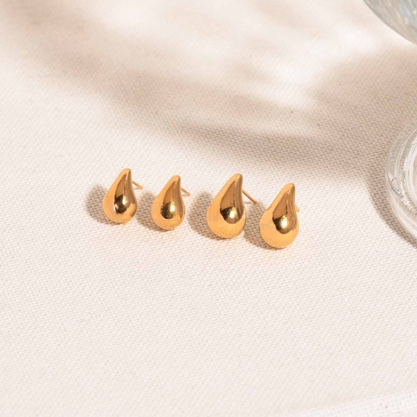 Small Large Teardrop Stud Earrings Dainty teardrop stud earrings and teardrop stud earrings on white textured surface 
