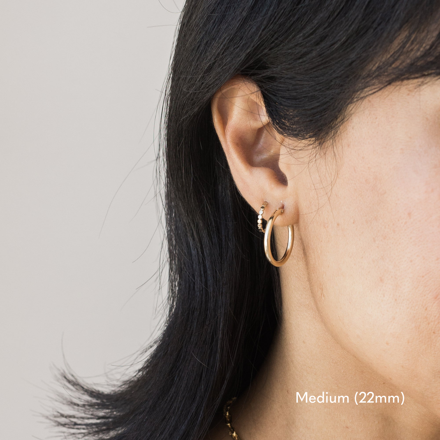 Woman wearing a single medium 22mm gold Everyday Hoop Earring on one ear. The photo is taken from the side, showing her earring, and hair pulled back,.

Small (13mm) Medium (22mm) Large (35mm) Everyday Hoop Earrings by Simple & Dainty Jewelry